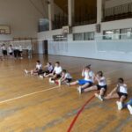 Dzieci siedzą na podłodze i ćwiczą.