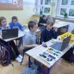 Uczniowie pracują na laptopach podczas warsztatów programowania.