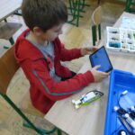 Uczeń programuje robota z klocków lego na laptopie.