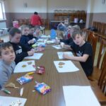 Dzieci siedzą przy stolikach ozdabiając pierniczki.