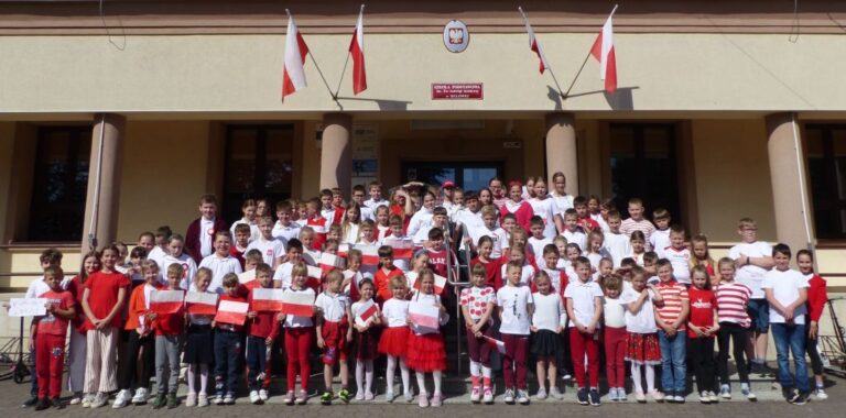 Uczniowie pozują w barwach biało - czerwonych przed szkołą