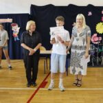 Nagrodzony uczeń pozuje do zdjęcia z jury