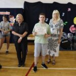 Nagrodzony uczeń pozuje do zdjęcia z jury